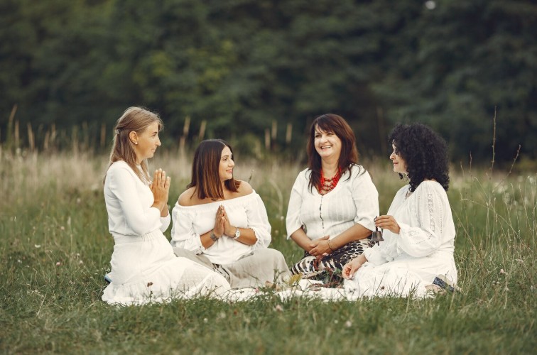 Group of women meditating together on meadow